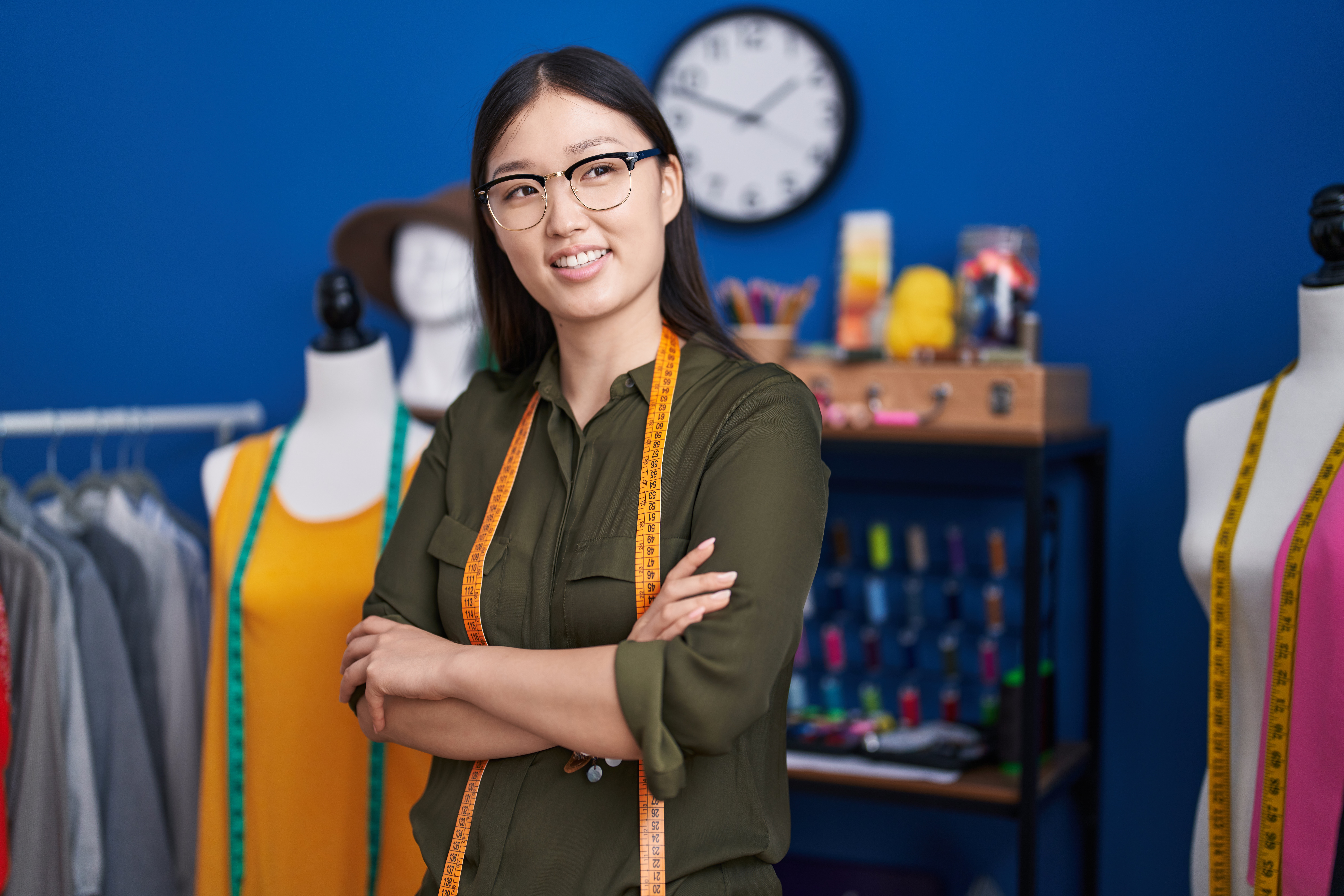 Chinese woman tailor smiling confident standing with arms crossed gesture at sewing studio